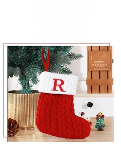 Gros plan d'une chaussette de Noël en tricot avec lettre R près du sapin