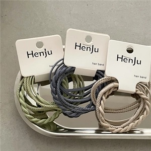 Detailed macro view of woven elastic hair bands in green and beige on a metal tray