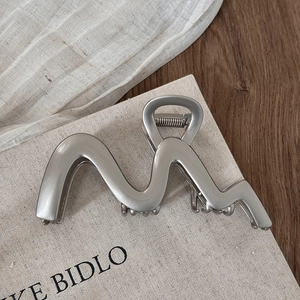 Dettaglio del grande fermaglio per capelli a onda in argento opaco con molla in metallo