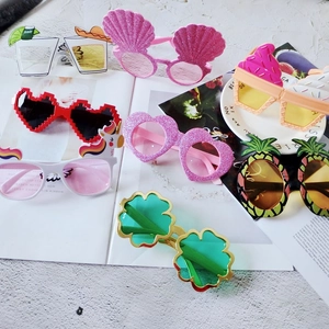 Colorful party sunglasses set in shell and pineapple shapes on a flat lay textured background