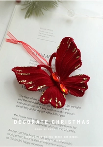 Detail of red flocked butterfly ornament with gold glitter and red gems on a book