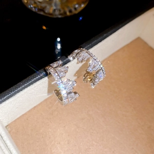 Macro shot of silver C-shaped earrings with sparkling cubic zirconia on a jewelry box edge