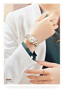 Elegance on wrist: steel calendar watch with silver and gold band on woman in white suit