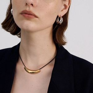 Détail du collier cordon noir avec tube doré 18k et boucles d'oreilles créoles argentées