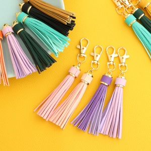 Colorful PU leather tassel keychains with gold metal lobster clasps on yellow background