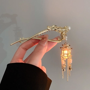 Detail of golden dragon hair clip with glowing lantern tassel and elegant pearl accents
