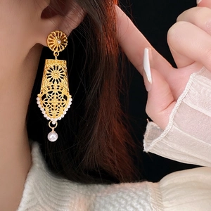 Orecchini pendenti vintage dorati con perle indossati da modella, vista laterale