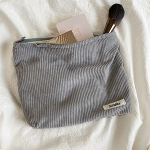 Gray corduroy makeup bag with zipper closure and spacious interior for cosmetics