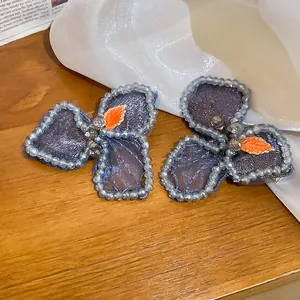 Detail of blue mesh floral hair clips with embroidery beads and orange leaf accents