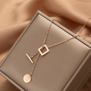 Detail of rose gold titanium necklace featuring a Good Luck disc and T-bar toggle clasp