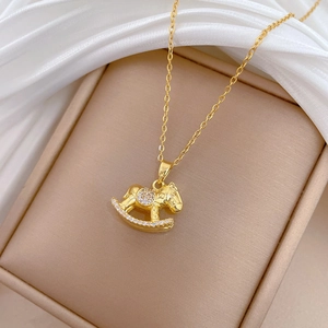 Detailed view of a gold rocking horse necklace with crystals in a premium gift box