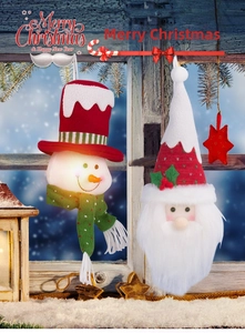 Detail of plush Snowman and Santa Claus ornaments with knitted hats on a snowy window