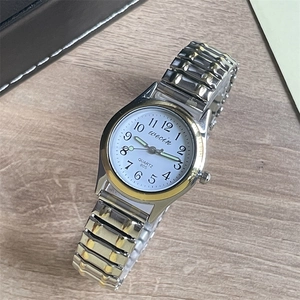 Close-up of a wecin quartz watch with silver and gold metal band on wooden desk