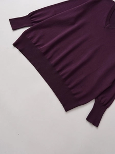 Dettaglio del maglione in maglia viola scuro con scollo a V e polsini a costine