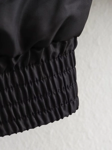 Detail of black flight jacket featuring elasticated ribbed cuffs and premium fabric texture