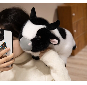Close-up of fluffy black and white plush cow toy being held to show soft texture