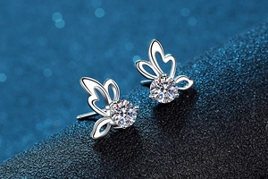 Macro shot of butterfly s925 silver stud earrings with 0.5ct moissanite on blue background