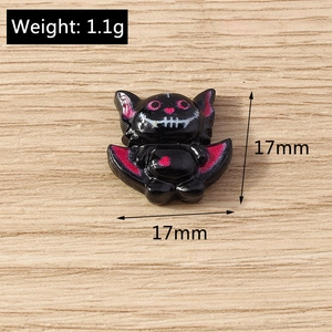 Detail of 17mm black resin Halloween bat charm with magenta glitter and skull face