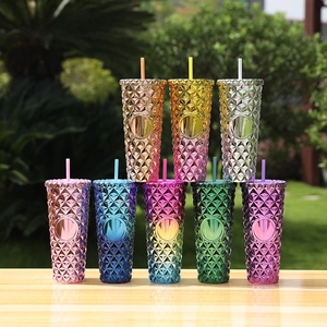 Detail view of multi-colored studded tumblers with straws arranged on a wooden table