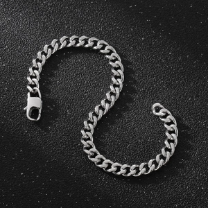 Detail of silver Cuban link bracelet with lobster clasp on a dark textured background