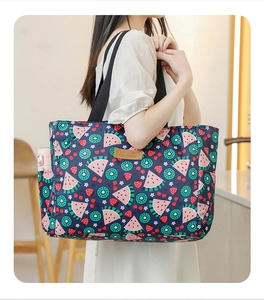 Detail of navy fruit-print picnic bag with side pocket for bottles and brown leather logo