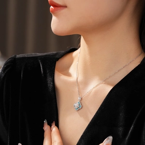 Detailed close-up of a zircon diamond flower and pearl pendant necklace on a black dress