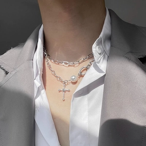 Close-up of double layer silver necklace with pearls and cross pendant on a model