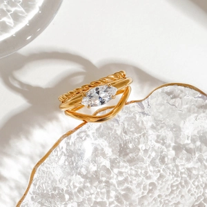 Gold layered stainless steel ring with a large marquise zircon on a glass tray