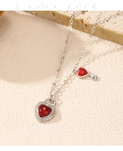 Detail of s925 silver heart lock necklace with red gemstone on stone background