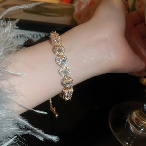 Detailed view of a gold heart link bracelet with sparkling heart-shaped zircons and adjustable clasp