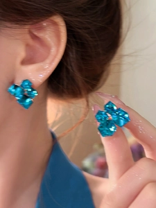 Macro shot of geometric blue crystal stud earrings on model showing sparkling facets