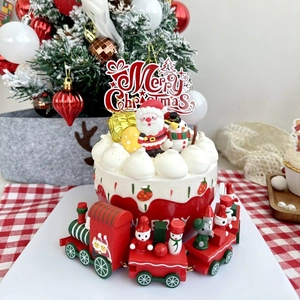 Macro view of Merry Christmas acrylic cake topper and miniature wooden toy train decoration