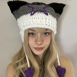 Detail of cat ear beanie with purple star patterns and long tassels on white background