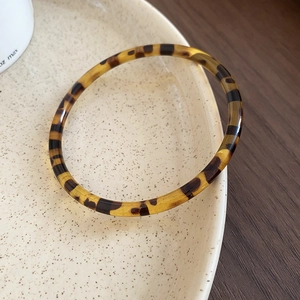 Detailed texture of amber leopard print acrylic resin bracelet on a ceramic plate