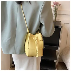 Detail of light yellow woven bucket bag with drawstring closure and adjustable strap