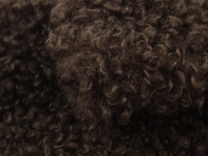 Detailed macro view of dark brown curly sherpa fleece fabric showing premium texture
