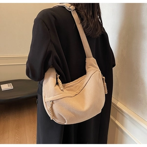 Detail of beige corduroy dumpling bag featuring adjustable strap and knotted side accents