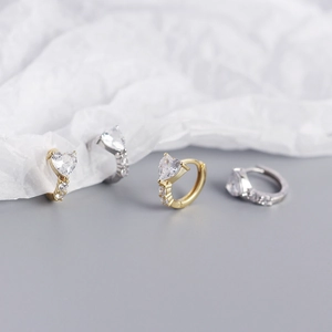 Macro detail of gold and silver S925 heart earrings with shimmering zircon settings