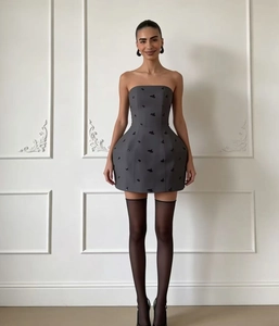 Detail van donkergrijze strapless jurk met strikborduursel en een gestructureerde rok