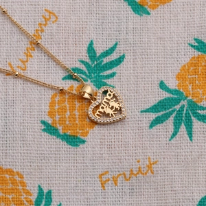 Close-up of golden heart pendant with mama lettering and zircon stones for Mother's Day