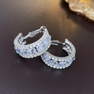 Macro shot of silver geometric hoop earrings with large square zircons and small diamonds