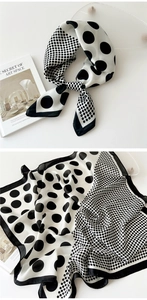 Detail of black and white polka dot silk scarf featuring smooth texture and elegant knotted style