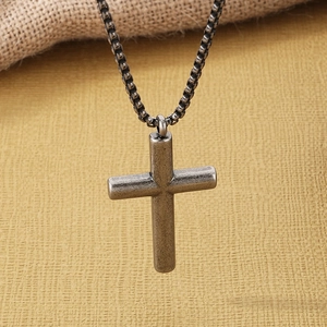 Close-up of vintage silver stainless steel cross pendant with detailed aged texture finish