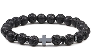 Macro detail of black volcanic lava rock beads with a metallic cross pendant on bracelet
