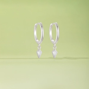 Macro shot of 925 sterling silver hoop earrings with sparkling rhombic zircon pendants