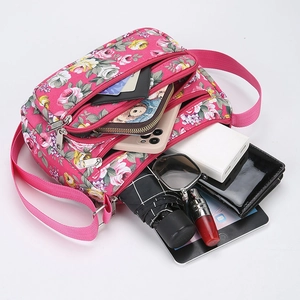 Pink floral printed crossbody bag showing large capacity with phone, wallet and tablet