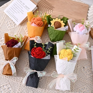 Detail of assorted handmade crochet flower bouquets on lace including sunflowers and roses