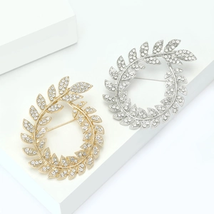 Elegant gold and silver olive leaf wreath brooches with rhinestones on white display