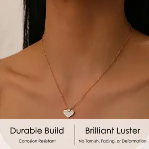 Close-up of gold heart pendant necklace with white shell inlay and zircon on a model