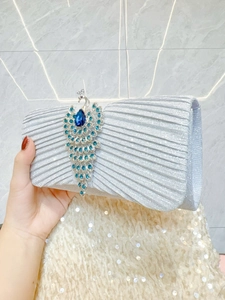 Elegant silver pleated evening clutch bag with a blue rhinestone peacock brooch